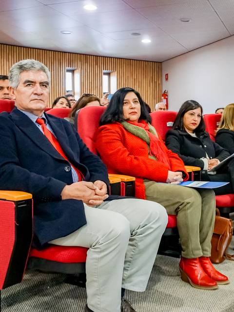 Un grupo de personas sentadas en una sala de conferencias, prestando atención a un evento.