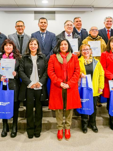Un grupo de personas sonrientes sostiene certificados en un evento formal.