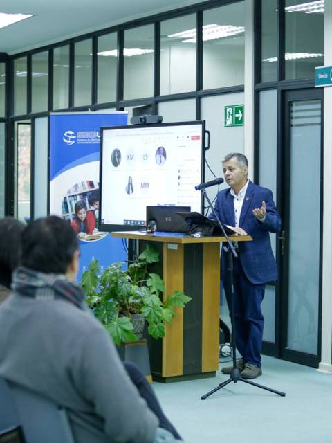 Un presentador habla frente a una audiencia en un salón de conferencias.