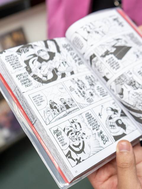 Una persona sostiene un cómic abierto en una librería.
