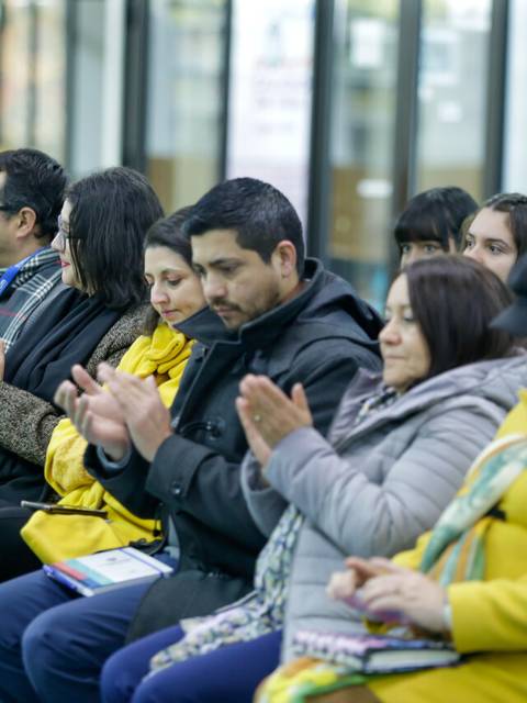 Un grupo de personas aplaudiendo durante un evento en un espacio interior.