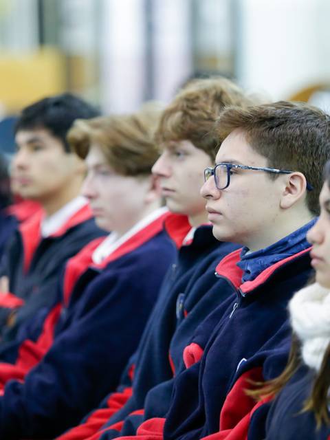 Un grupo de estudiantes sentados en un aula escuchando atentamente.