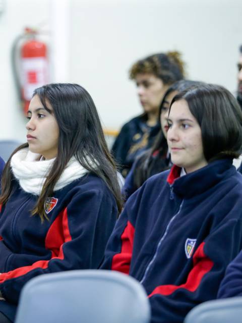 Un grupo de estudiantes sentados prestando atención en un evento.