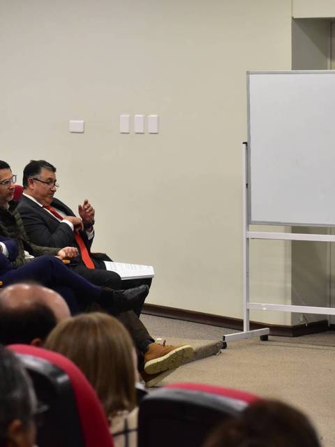 Una oradora se dirige a una audiencia en un evento en un auditorio.