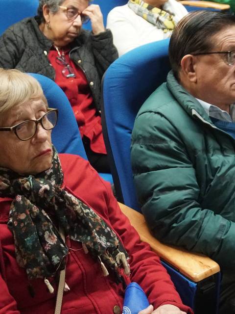 Un grupo de personas sentadas en una sala mirando hacia el frente.