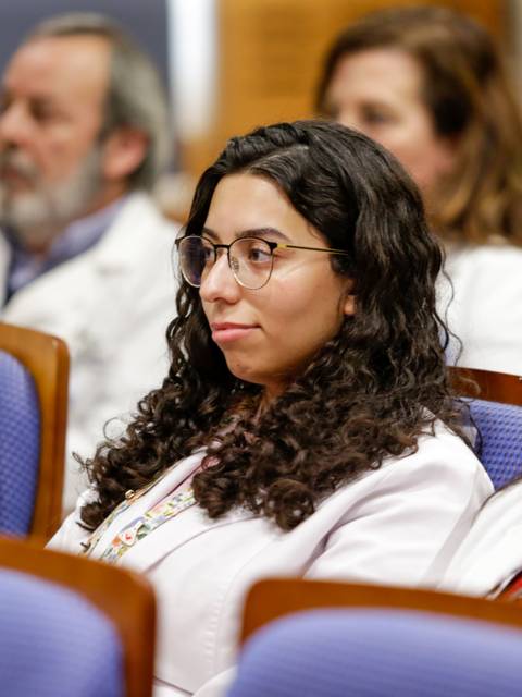 Un grupo de personas con batas blancas escuchando atentamente en un evento.