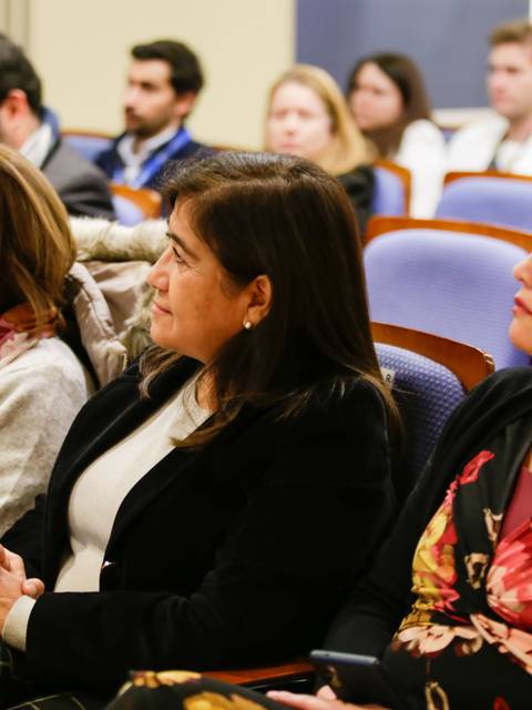 Un grupo de mujeres sentadas escuchando atentamente en una convención o conferencia.