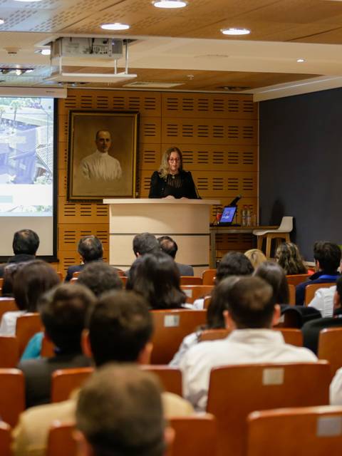 Una presentación en un auditorio con un proyector y asistentes en sus asientos.