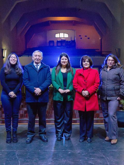 Un grupo de cinco personas posando en un escenario iluminado.