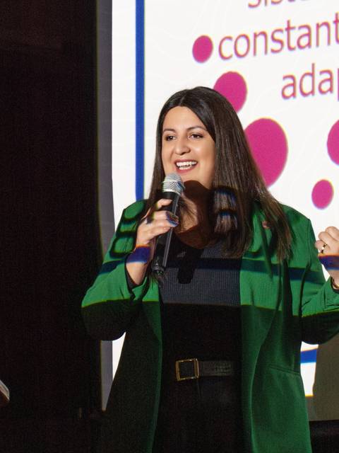 Una mujer habla apasionadamente al público mientras sostiene un micrófono.