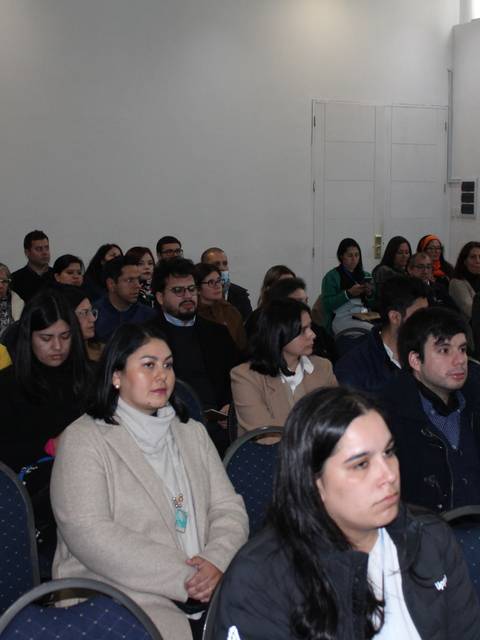Un grupo de personas sentadas en un evento o reunión en un salón.