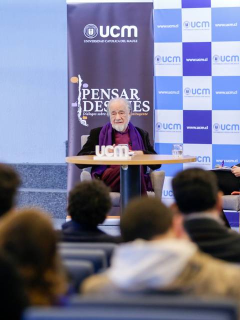 Una charla en la Universidad Católica de Murcia con un ponente y una moderadora frente a un público atento.
