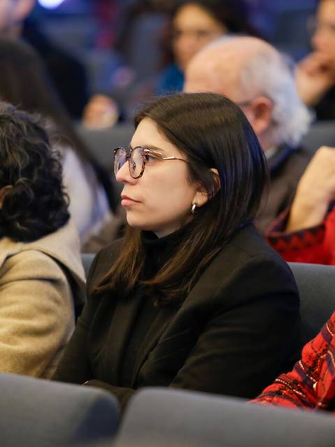 Un grupo de mujeres sentadas en un evento observando atentamente.
