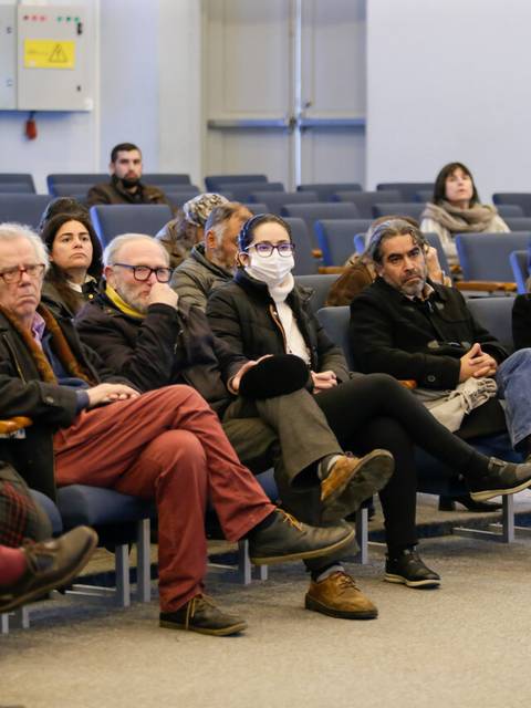 Un grupo de personas sentadas en un auditorio, asistiendo a un evento.