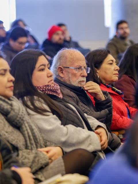 Una audiencia atenta en un evento, compuesta por personas sentadas en filas.
