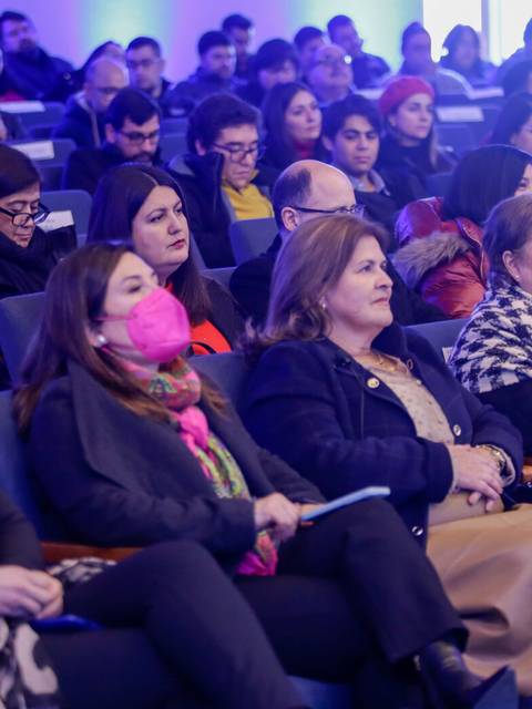 Una multitud de personas sentadas en un auditorio prestando atención a una presentación.
