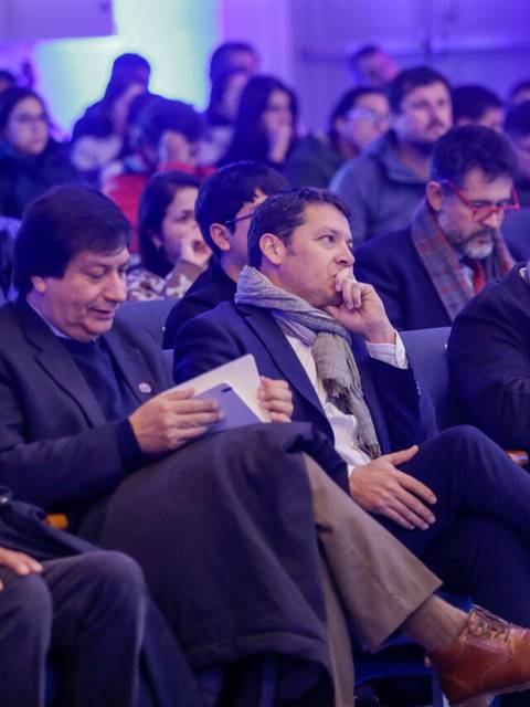 Un grupo de personas sentadas en un evento, prestando atención al orador.