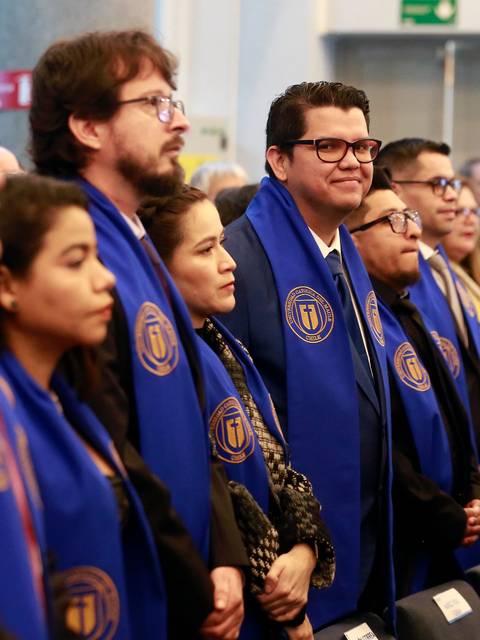 Un grupo de personas con bufandas azules observan un evento en un salón.