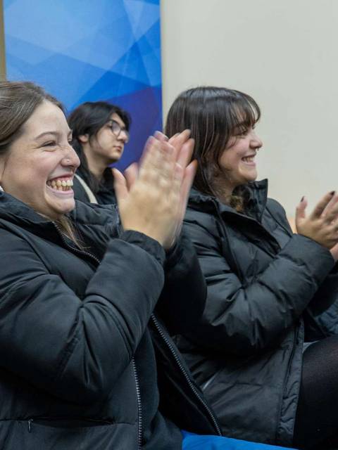 Un grupo de personas aplaudiendo durante un evento en un ambiente alegre.