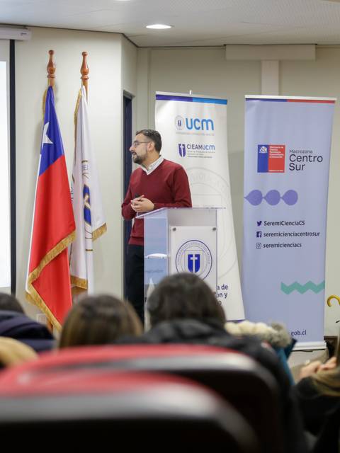 Un conferencista presenta información en una sala con estudiantes atentos.