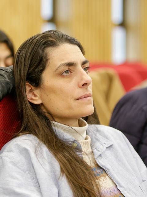 Una mujer observa atentamente mientras está sentada en un auditorio.