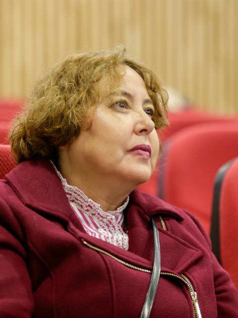 Una mujer sentada en un auditorio, observando atentamente.