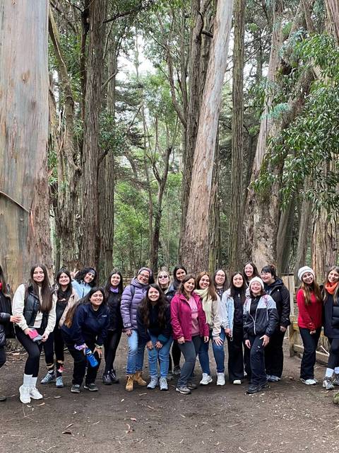 Un grupo de personas sonrientes posando en un bosque de eucaliptos.