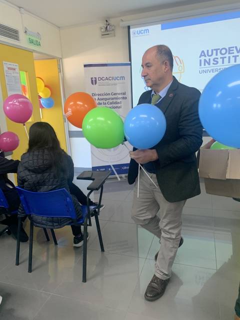 Un hombre sosteniendo globos de colores en una sala de un evento.