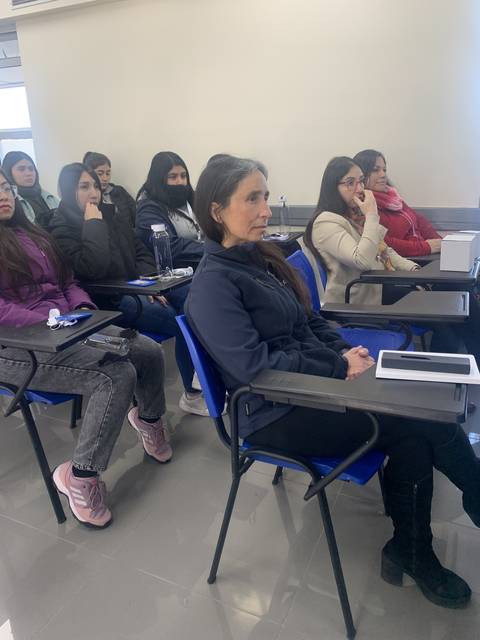 Un grupo de mujeres sentadas en un salón de clase prestando atención.