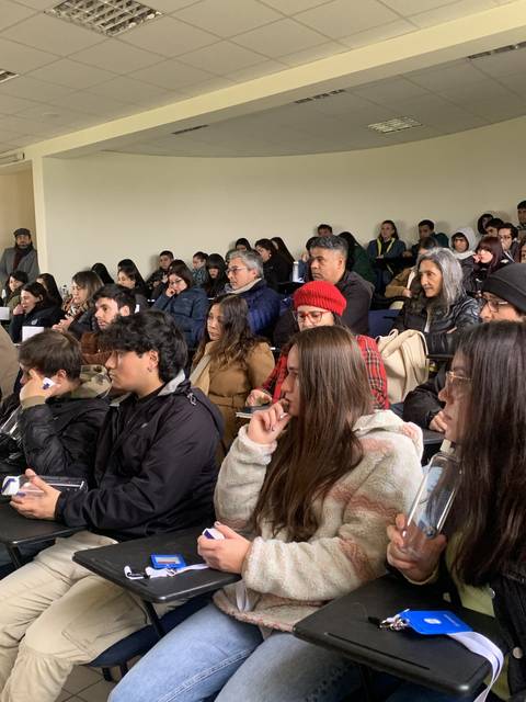 Un grupo de personas sentadas en un aula, atentos a una presentación o charla.