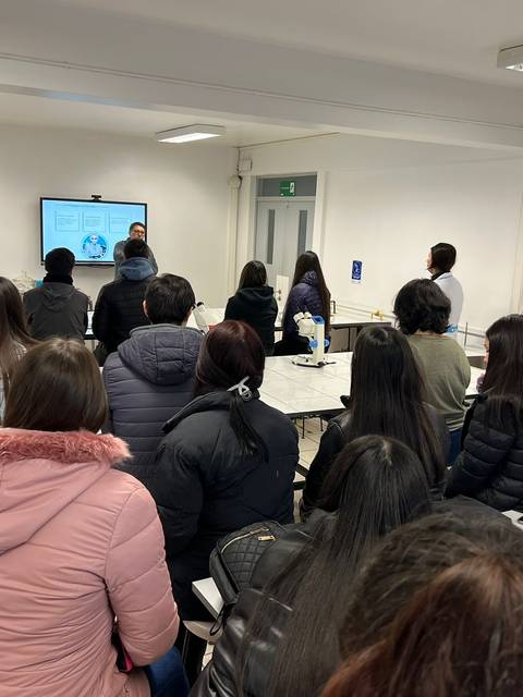 Un grupo de personas asiste a una presentación en un salón de clases.