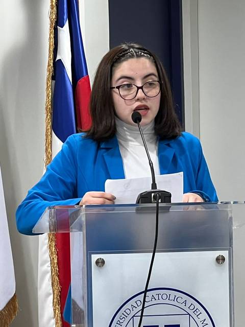 Una joven está presentando en un podio en un evento académico.