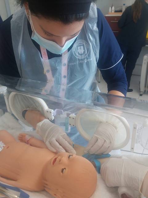 Una profesional de la salud está atendiendo a un bebé simulado en un entorno clínico.