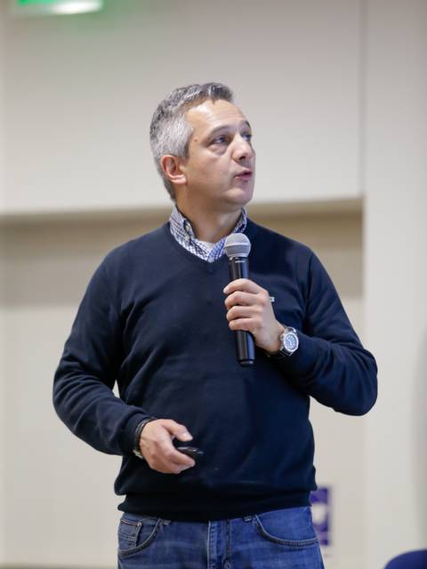 Un hombre está de pie hablando con un micrófono en la mano durante una presentación.