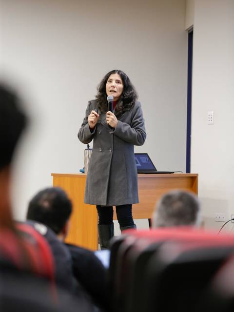 Una mujer está hablando frente a un público en un auditorio.