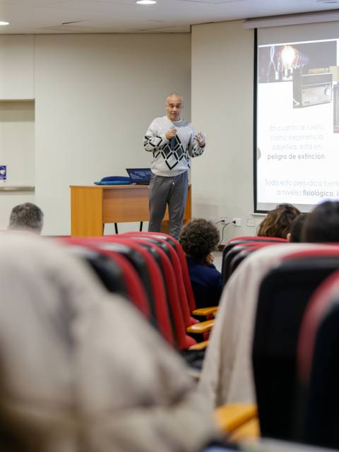 Un hombre presenta un tema en una conferencia ante una audiencia sentada.