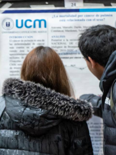 Un grupo de estudiantes observa un cartel informativo en una universidad.
