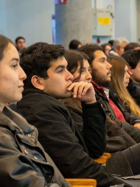 Un grupo de jóvenes atentos escucha durante un evento en un auditorio.