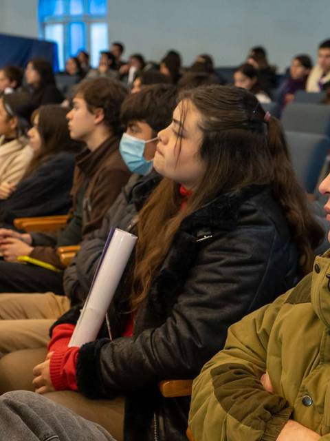 Un grupo de personas sentadas en un auditorio prestando atención durante una presentación.