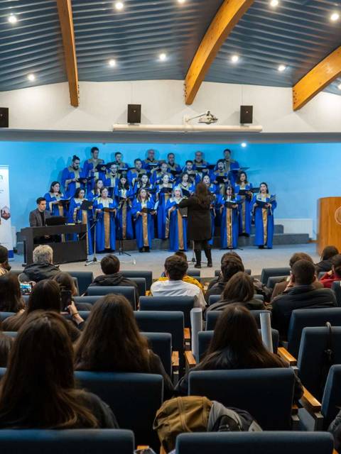Un coro se presenta en un auditorio frente a un público sentado.