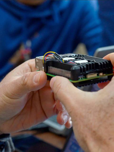 Una persona sostiene un dispositivo electrónico en sus manos mientras otra persona observa.