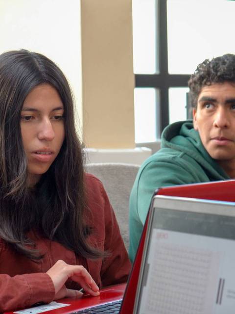 Tres personas están trabajando en laptops en un ambiente de estudio.