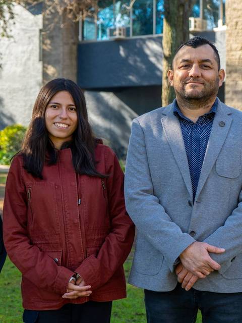 Un grupo de cuatro personas sonrientes posan en un entorno de jardín frente a un edificio.