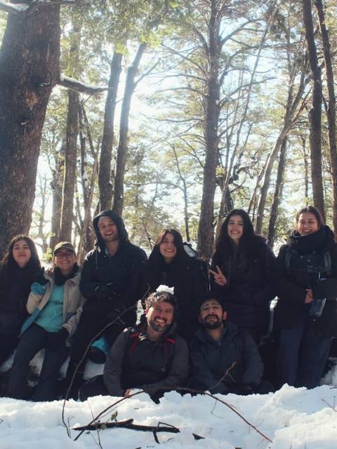Grupo de amigos posando en un paisaje nevado entre árboles.