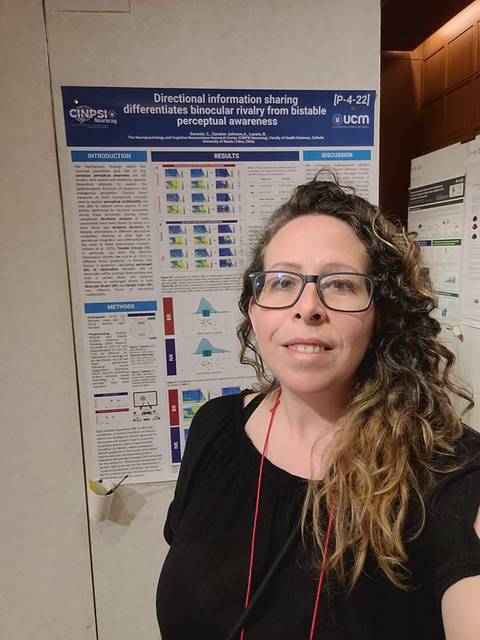 Una persona posa frente a un cartel de investigación científica en un congreso.