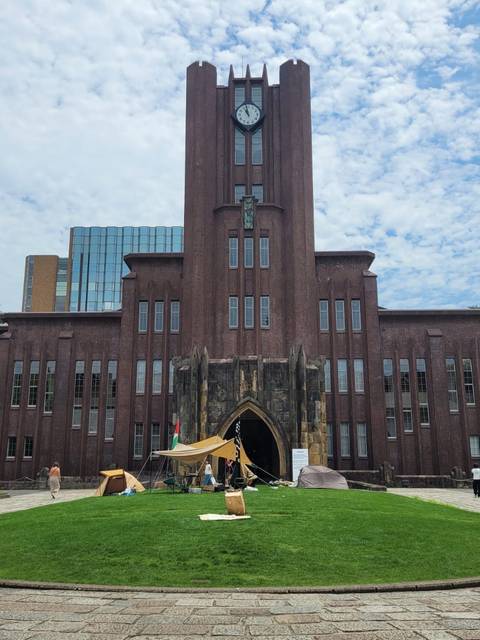 Una gran edificación con un diseño arquitectónico distintivo y un reloj en la parte superior, ubicada en un espacio verde.