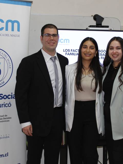 Un grupo de tres personas posando frente a un banner de la universidad.