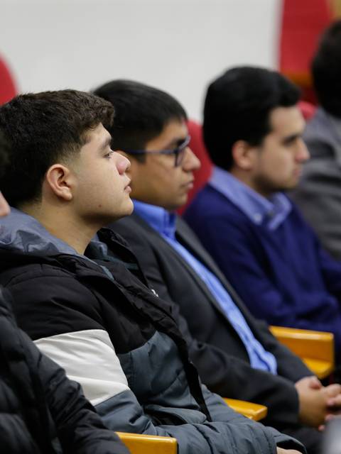 Un grupo de jóvenes sentados en un auditorio escuchando atentamente.