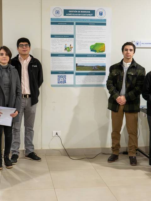 Un grupo de personas posando frente a un cartel en un evento académico.