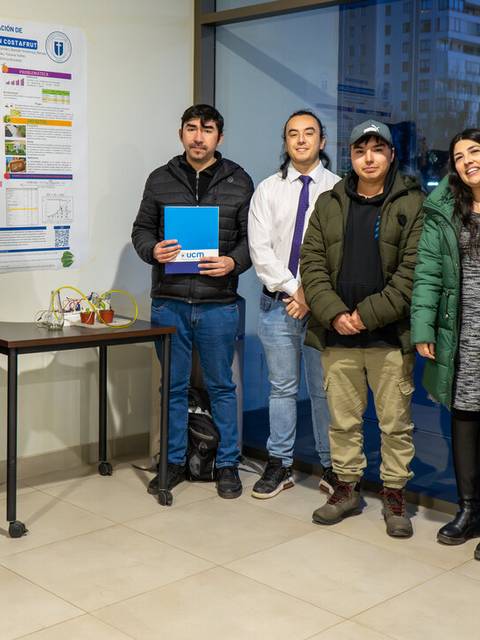 Grupo de personas posando junto a un póster en un evento académico.